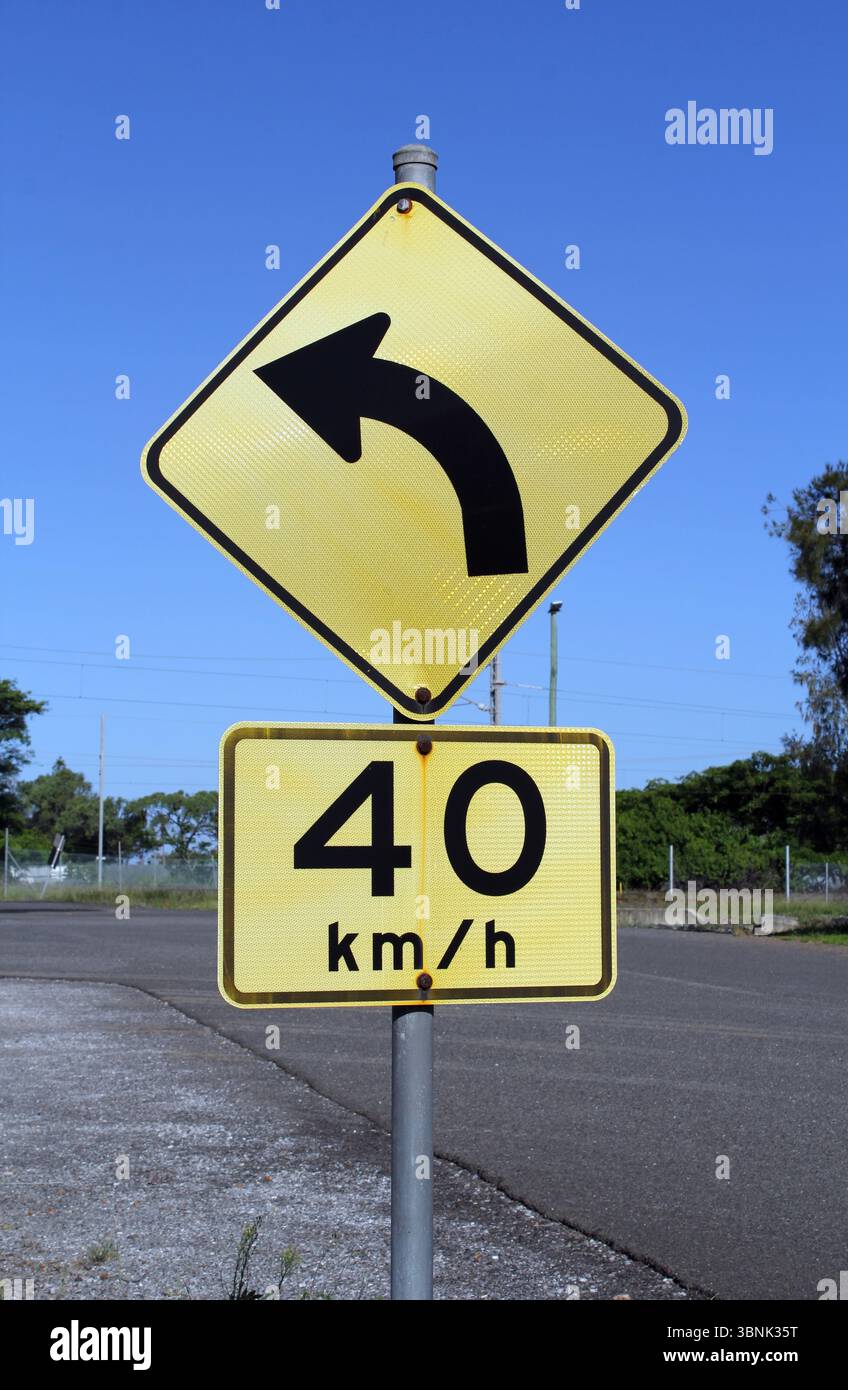 Tournez à gauche et les panneaux de limitation de vitesse montés sur un poteau simple à côté d'une route Banque D'Images