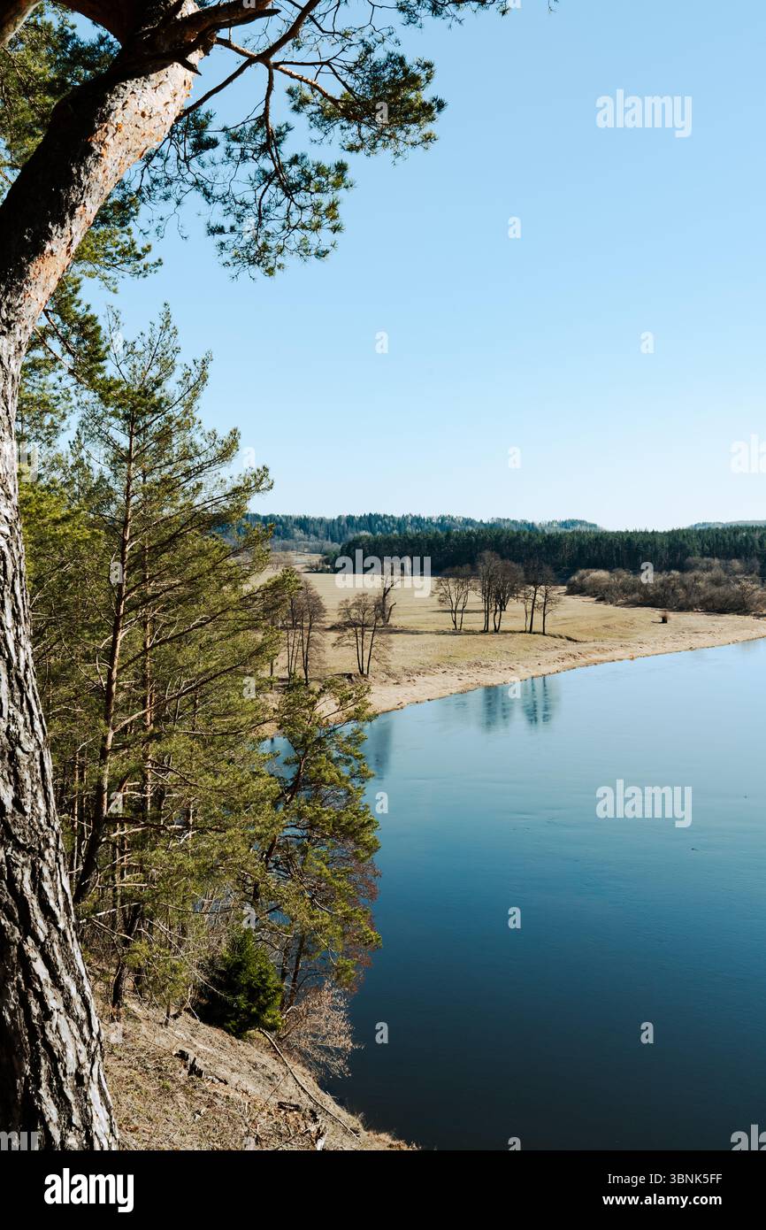 Une rivière Azur encadrée par des silhouettes d'arbres sous la lumière douce du jour. Un paysage naturel pittoresque, parfait pour les thèmes du voyage, de la nature et de la paix intérieure. Banque D'Images
