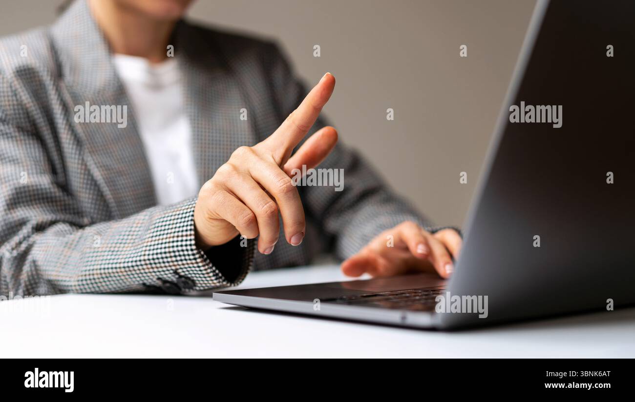 Maquette d'une femme faisant un geste de glissement tout en travaillant sur un ordinateur portable Banque D'Images