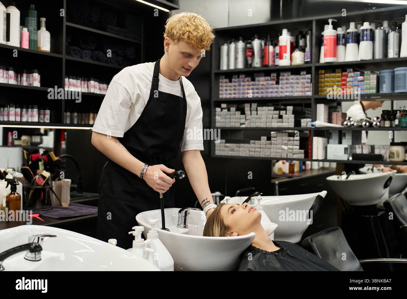 Un styliste lave habilement les cheveux d'un client dans un salon de beauté chic, mettant en valeur les tendances actuelles. Banque D'Images