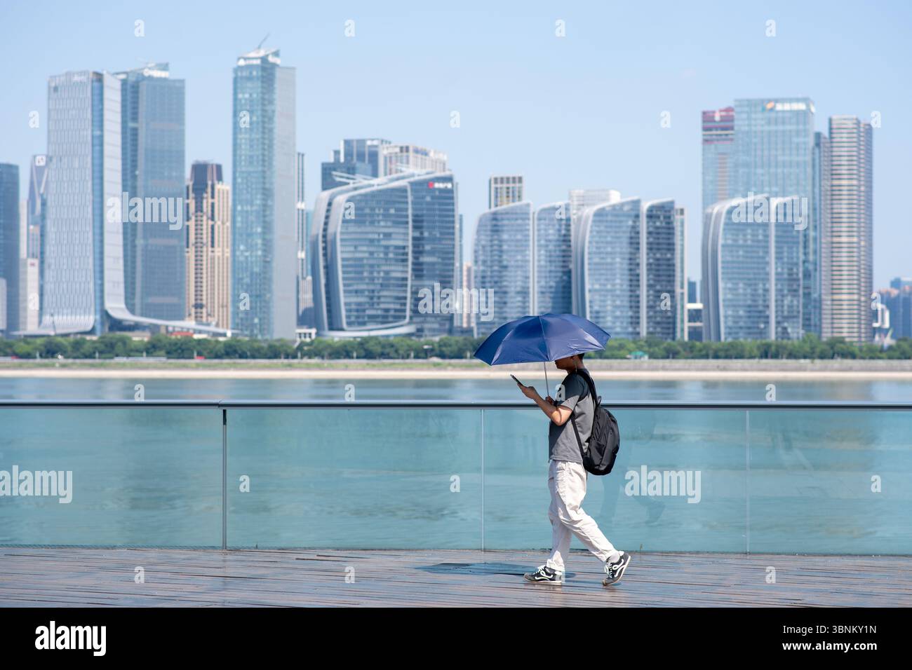 Hangzhou, province chinoise du Zhejiang. 3 juillet 2025. Un homme tenant un parapluie marche le long de la rivière Qiantang à Hangzhou, dans la province du Zhejiang de l'est de la Chine, le 3 juillet 2025. Hangzhou a émis une alerte de chaleur orange jeudi. Crédit : Jiang Han/Xinhua/Alamy Live News Banque D'Images