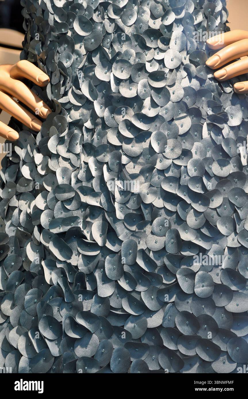 Mains d'un mannequin de mode sur une robe bleu clair faite de pétales de tissu Banque D'Images