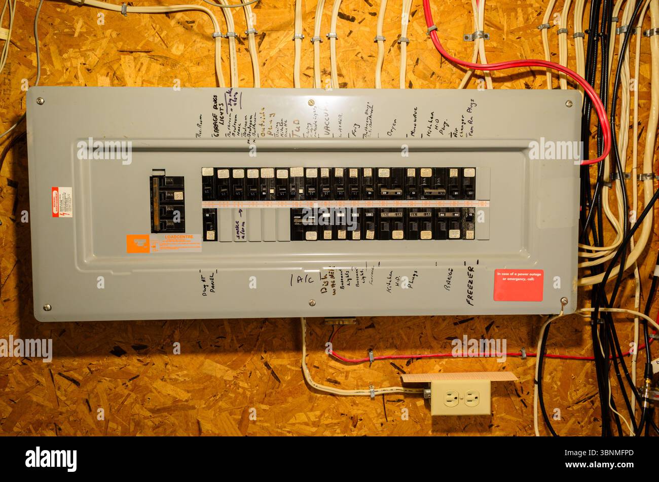 Gros plan d'un panneau de disjoncteur résidentiel et du câblage monté sur un mur de sous-sol Banque D'Images