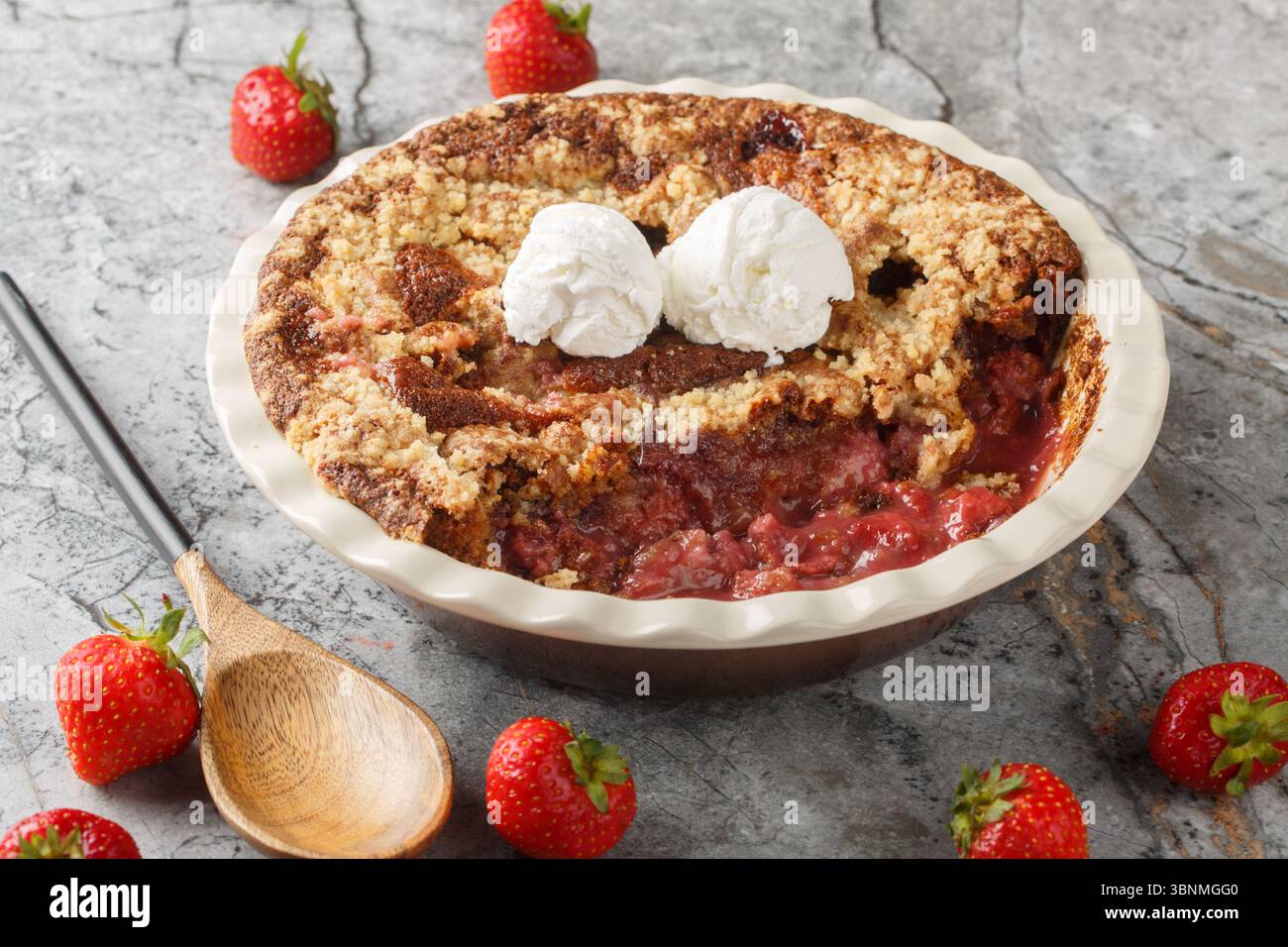 Tarte cordonnier aux fraises avec crème glacée gros plan dans un plat de cuisson sur la table. Horizontal Banque D'Images