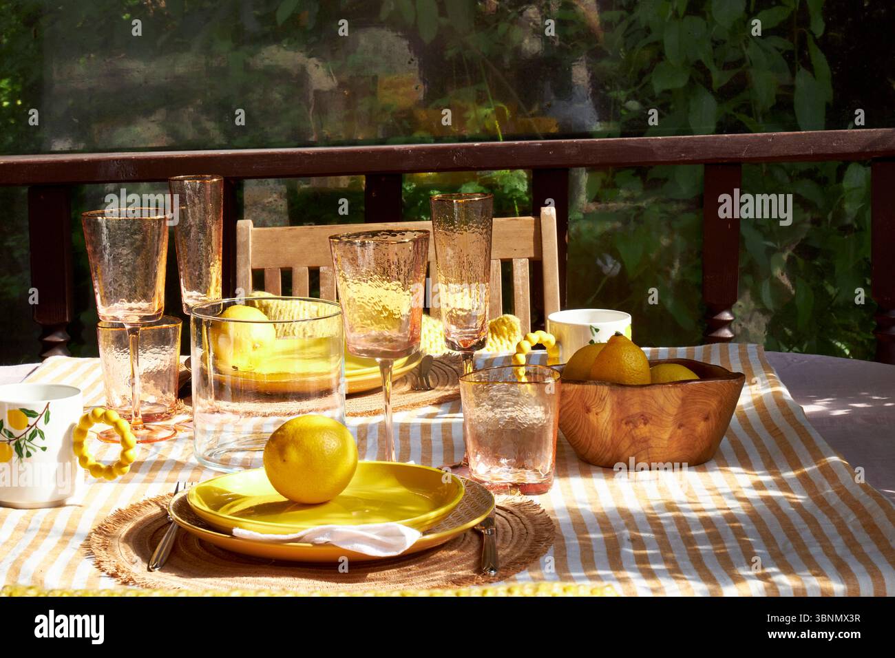 Une table d'été lumineuse décorée de citrons, d'hortensias vertes et de verrerie. La lumière du soleil déverse à travers les plantes suspendues, créant une atmosphère chaleureuse et joyeuse Banque D'Images
