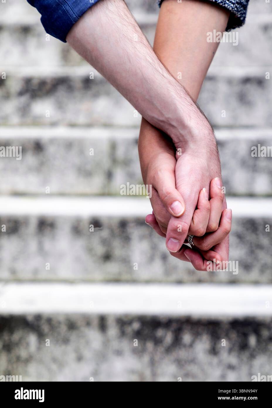 Un couple tient les mains, les doigts entrelacés, avec un anneau visible sur une des mains. Banque D'Images