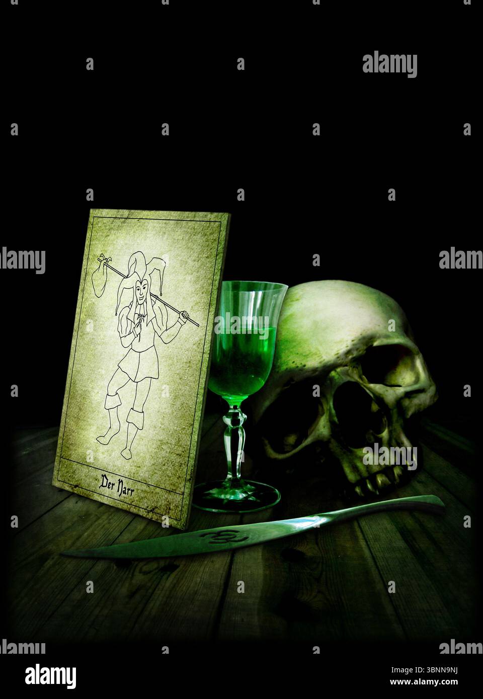 Un crâne, verre avec absinthe, carte de tarot, bouffon, joker, couverts à absinthe Banque D'Images