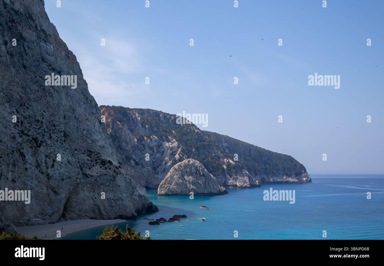 superbe vue panoramique sur une plage insulaire grecque isolée avec d'imposantes falaises blanches, une mer turquoise vibrante et un ciel bleu clair par une journée d'été ensoleillée. Banque D'Images