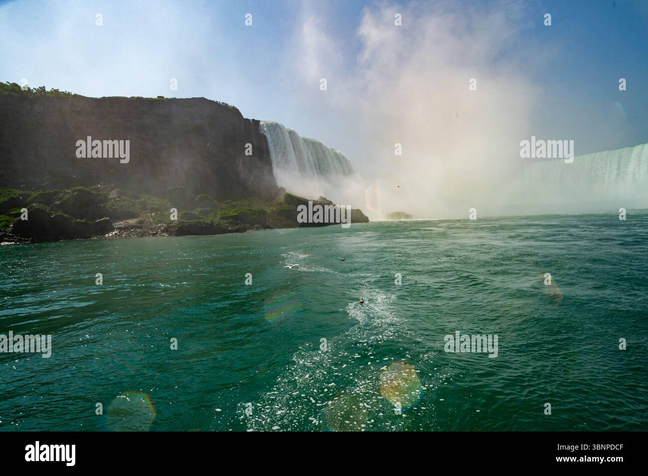 Vue artistique au niveau du bateau approchant des chutes Niagara Horeshoe sur la rivière Niagara, avec une eau verte et agitée, des gouttes diffractées arc-en-ciel et une brume montante. Banque D'Images