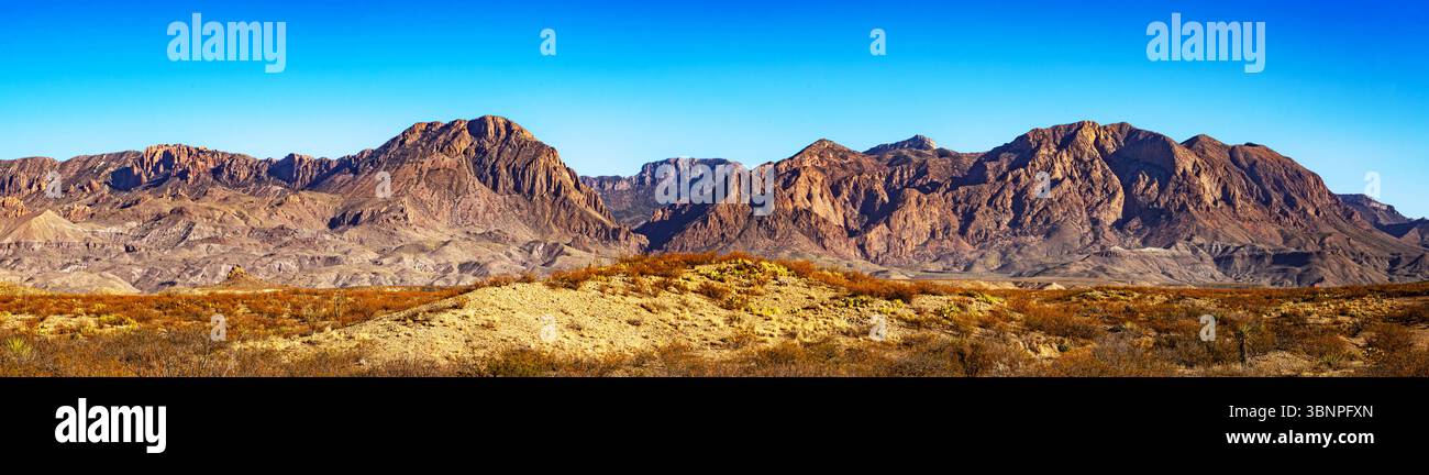 Vue panoramique sur les montagnes désertiques accidentées dans le parc national de Big Bend sous un ciel bleu vif. La géologie crée un contraste spectaculaire à travers le paysage. Banque D'Images