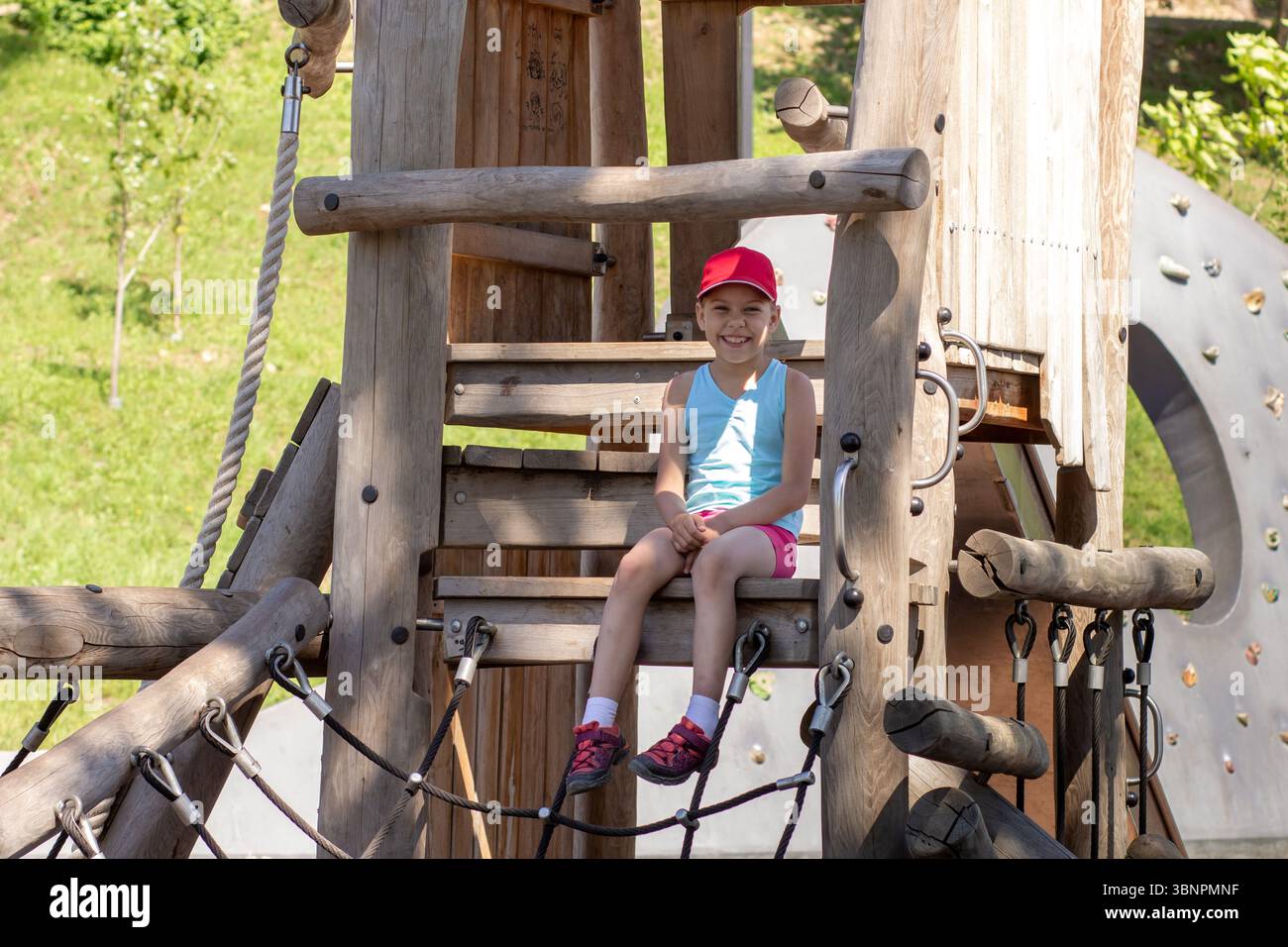 Enfant caucasien heureux et souriant 7 8 ans assis sur un paysage de jeu en bois Banque D'Images