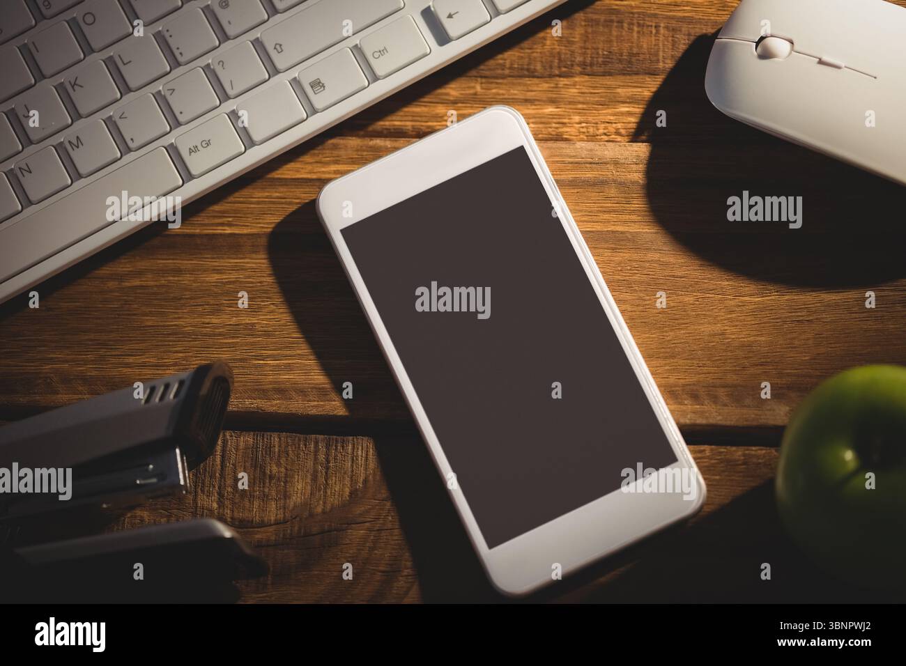 La conception plate montre smartphone blanc reposant sur le bureau avec clavier, souris, banques d'alimentation et pomme Banque D'Images