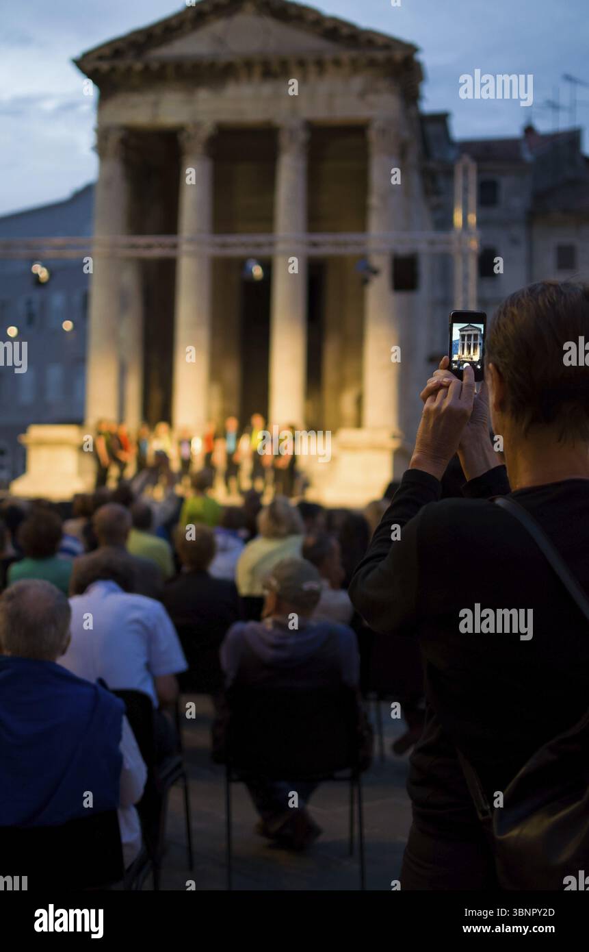 La prise d'un snapshot de tourisme avec le Smartphone d'un programme culturel en soirée à la verticale Banque D'Images
