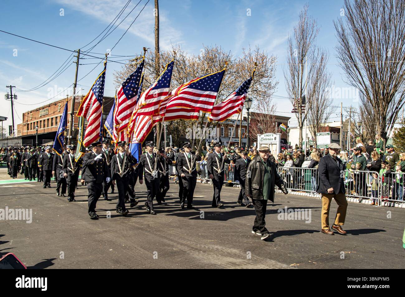 Lindenhurst, New York, États-Unis, 30 mars 2024 - des marcheurs en uniforme portant des drapeaux américains marchent fièrement dans Une rue ensoleillée pendant Une parade, avec Un Livel Banque D'Images