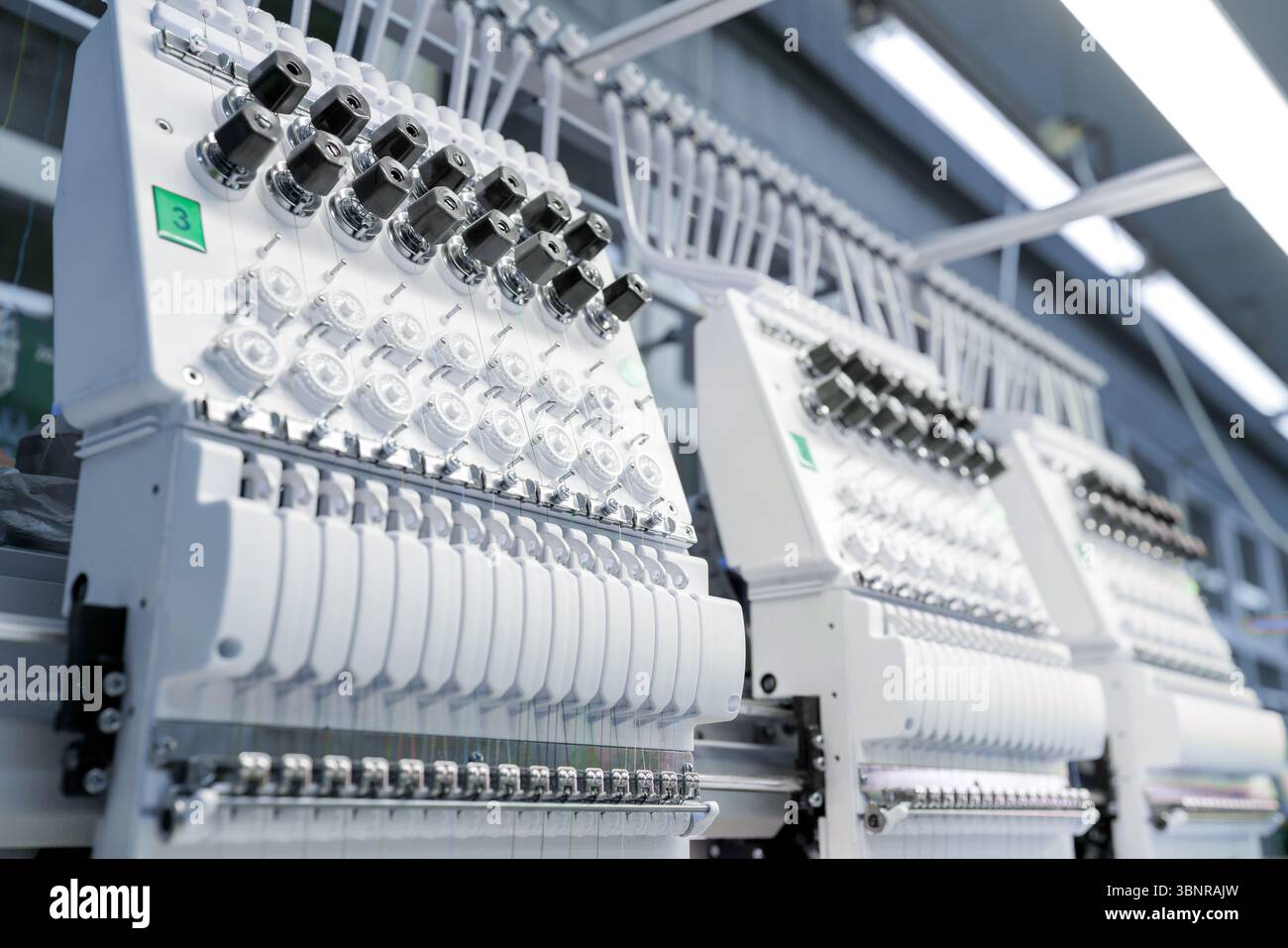 Gros plan de la machine à broder avancée travaillant sur le tissu, montrant le processus de couture industriel et la production textile Banque D'Images