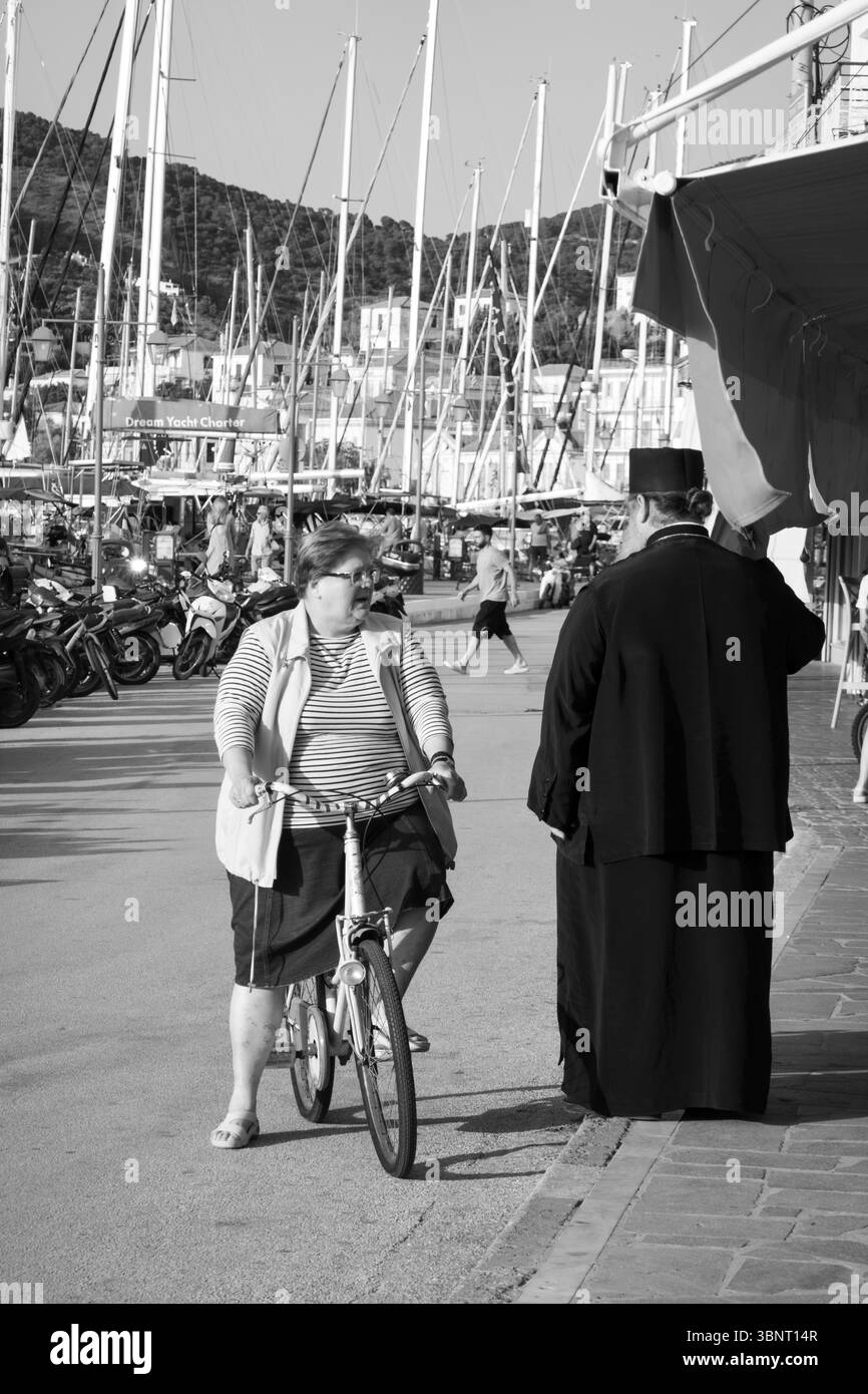 Femme à vélo parlant à un prêtre orthodoxe dans la ville de Poros, Poros, Golfe Saronique, îles grecques, Grèce, Europe Banque D'Images
