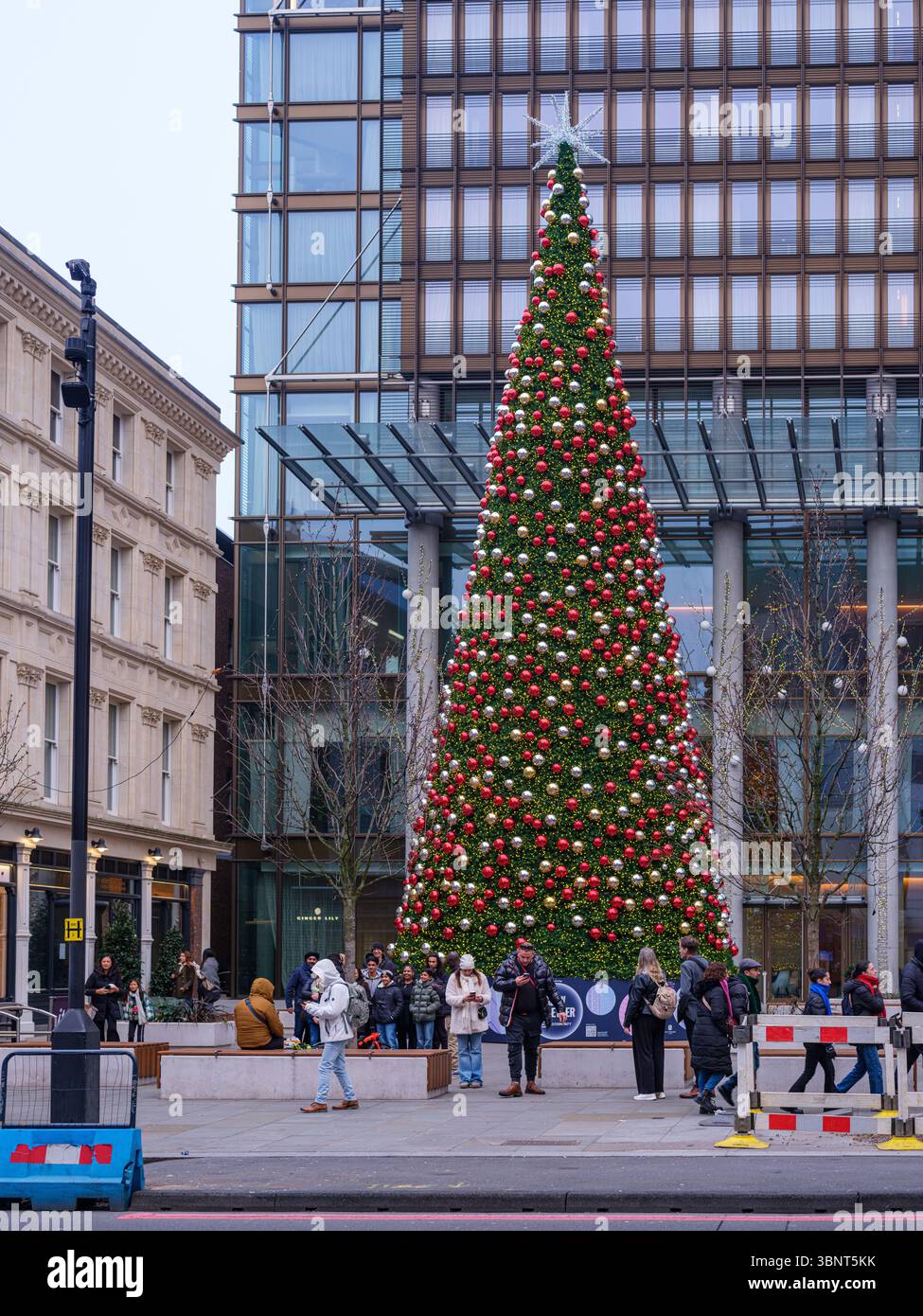Royaume-Uni, Londres, 9 décembre 2024. Les gens se rassemblent autour d'un grand arbre de Noël décoré devant un bâtiment moderne en verre près de Liverpool Street S. Banque D'Images