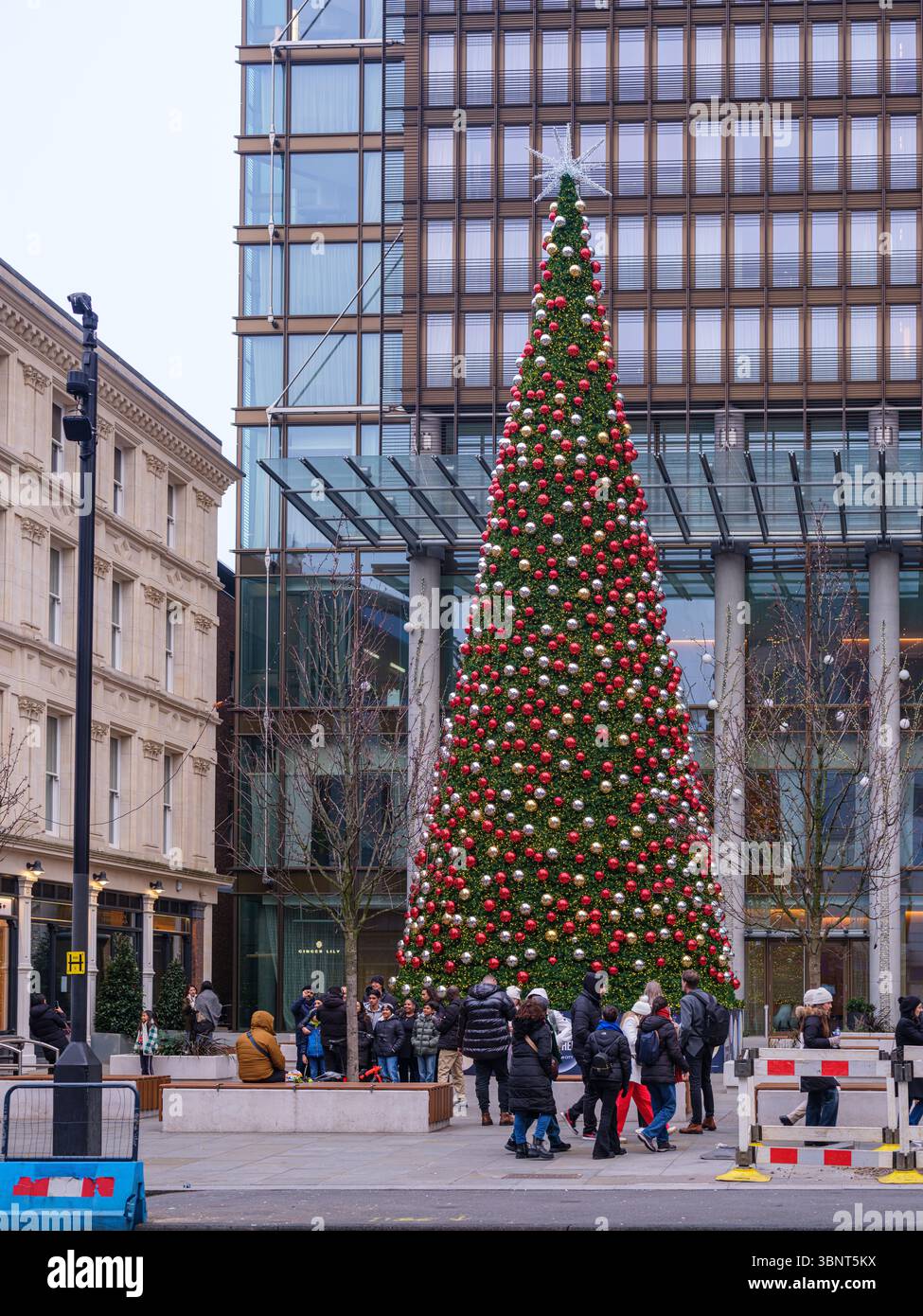 Royaume-Uni, Londres, 9 décembre 2024. Les gens se rassemblent autour d'un grand arbre de Noël décoré devant un bâtiment moderne en verre près de Liverpool Street S. Banque D'Images