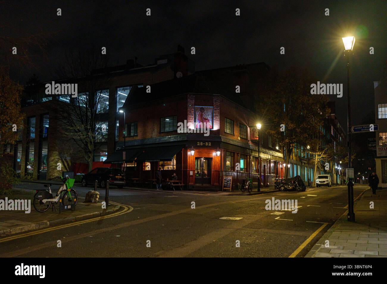 Royaume-Uni, Londres, 13 juillet 2025. Vue de nuit d'un coin calme dans l'est de Londres avec un pub éclairé et un trottoir humide après la pluie. Banque D'Images