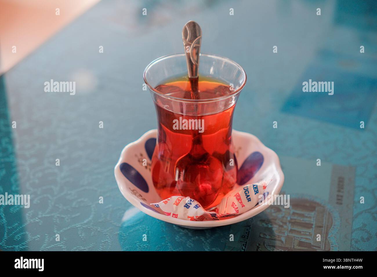 Verre de thé turc sur la table, thé noir traditionnel Cay, boisson chaude ambre dans le verre en forme de tulipe, détail de la culture du thé, scène d'hospitalité quotidienne Banque D'Images