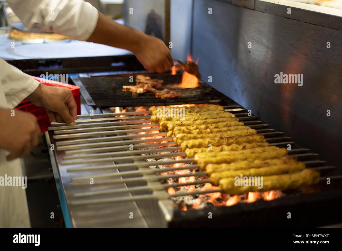 Sheffield 25 juin 2019 : feu incandescent pendant que les kebabs de poulet sont cuits sur du charbon sur le grill - dans la cuisine de l'Agha Lounge Banque D'Images