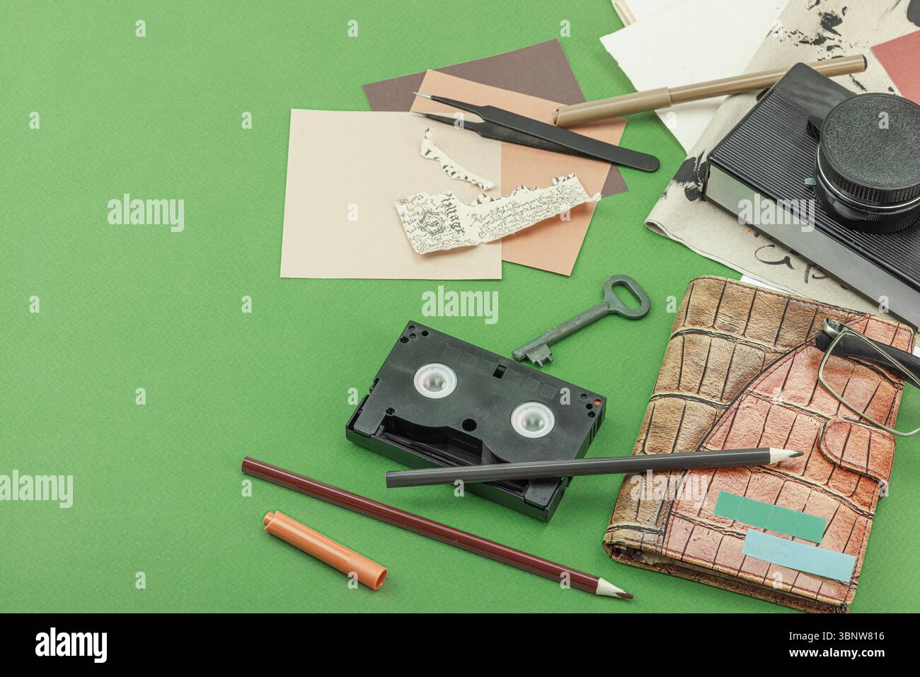 Plat avec appareil photo vintage, cassette, cahier, clé et outils de recherche sur fond vert, symbolisant le journalisme, OSINT, et la poursuite de la vérité, Banque D'Images