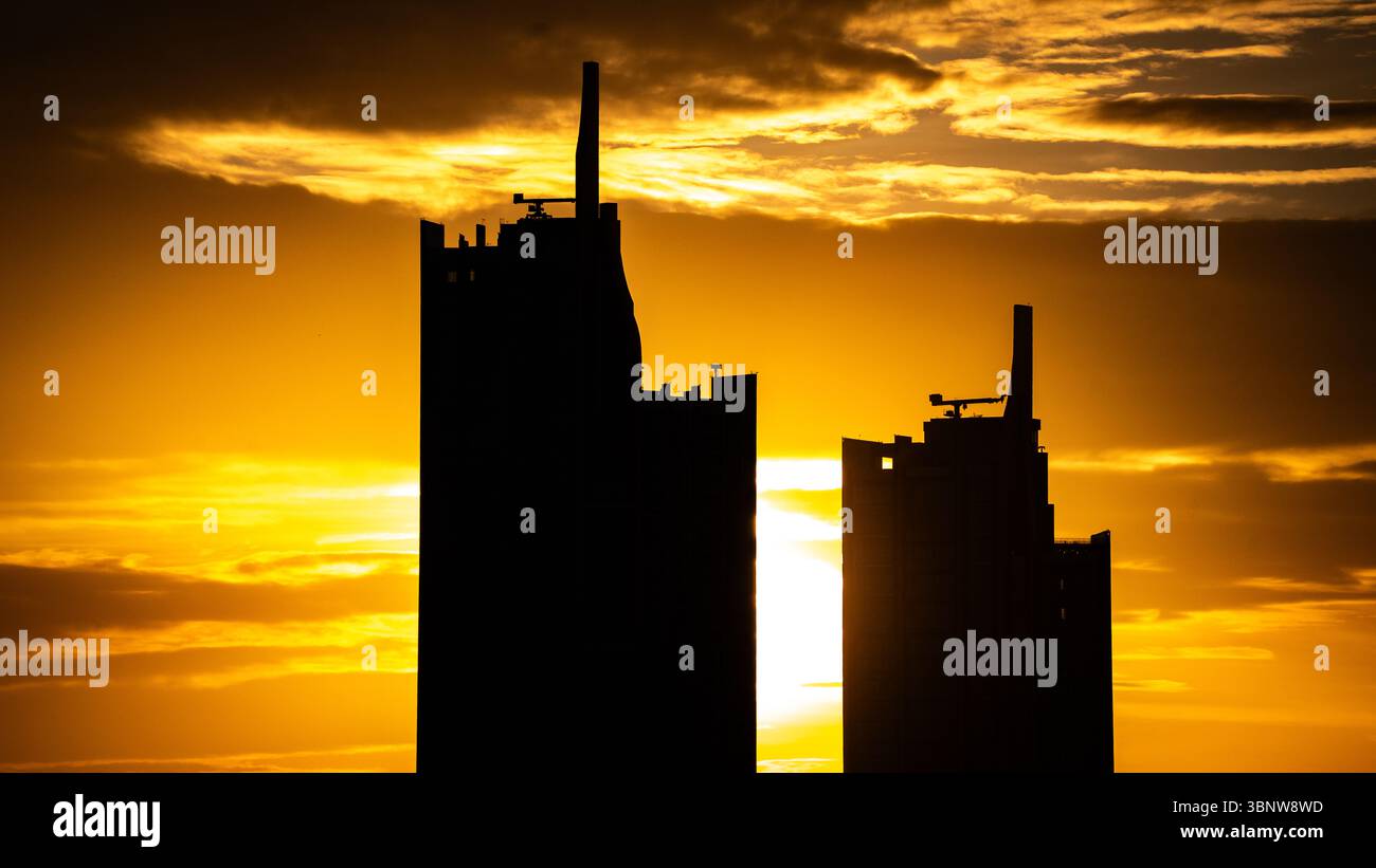 Immeubles de grande hauteur dessinés contre un coucher de soleil doré ardent Banque D'Images