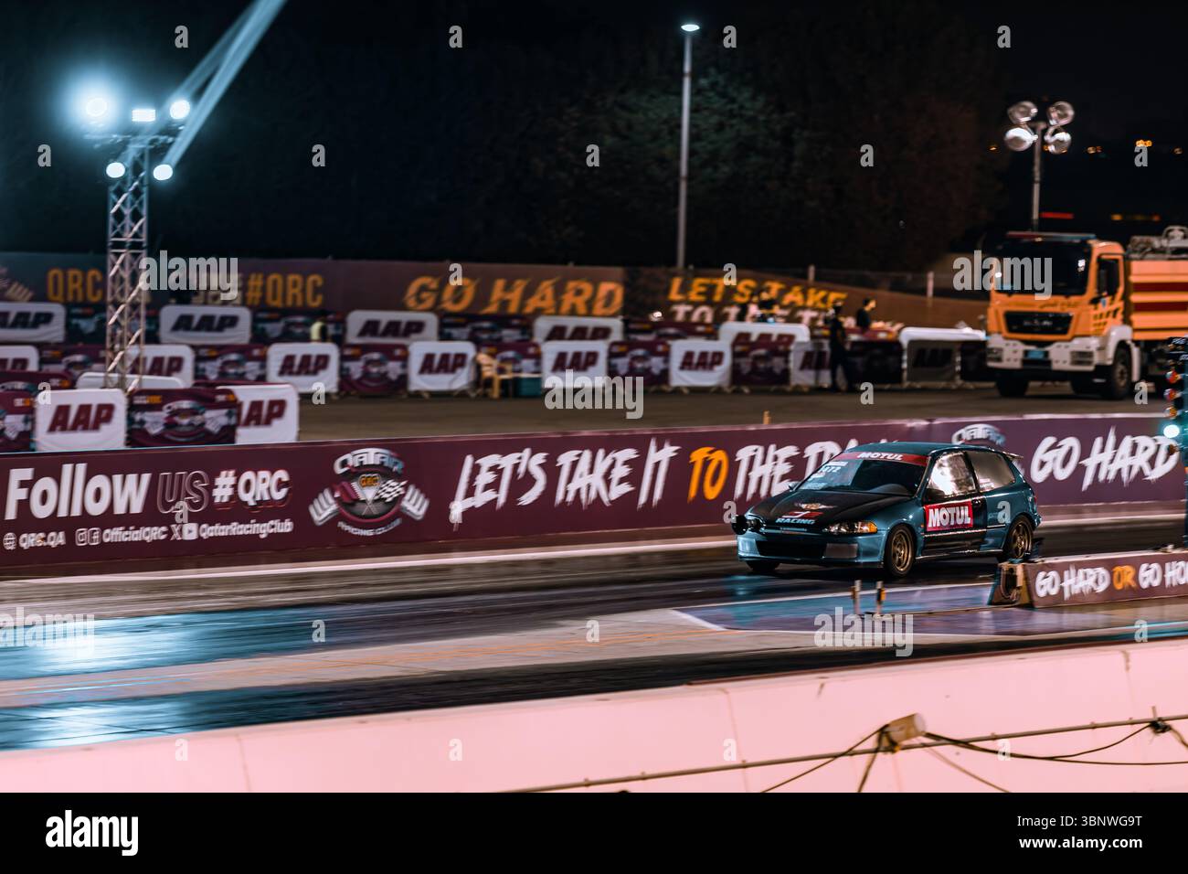 Motion blur course de dragsters nocturne mettant en vedette des voitures en compétition sur la piste avec des spectateurs à proximité Banque D'Images