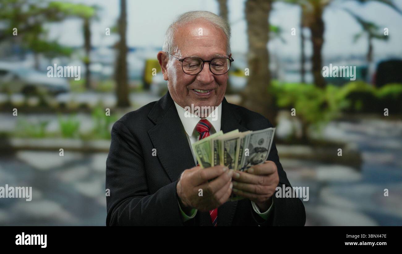 Homme senior en costume comptant nous dollars à l'extérieur sur la rue de la ville, exprimant le succès et la richesse dans un cadre urbain. Banque D'Images