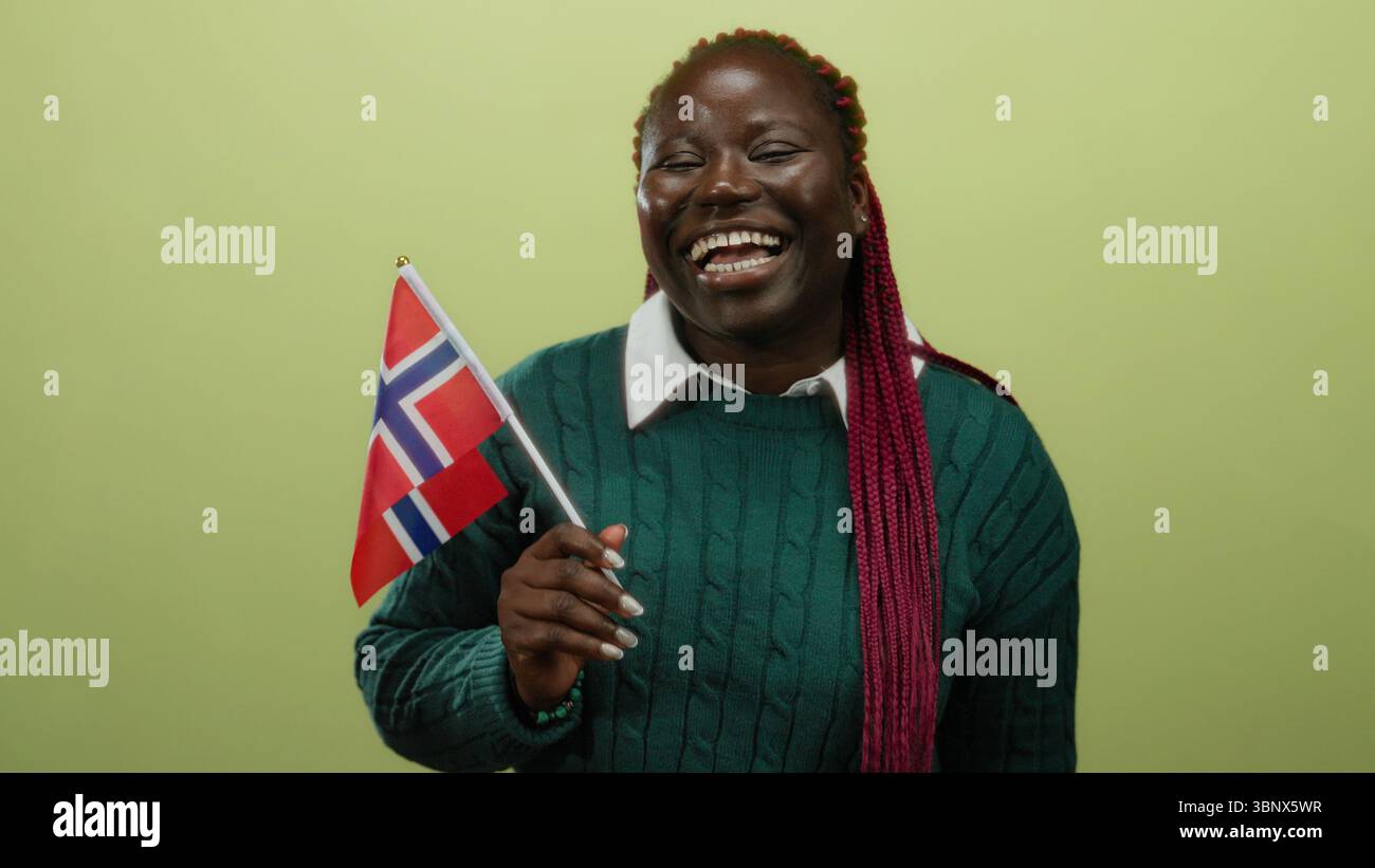 Femme tenant le drapeau norvégien sur fond jaune dans un cadre joyeux isolé, mettant en valeur la fierté culturelle et le patrimoine avec une expression vibrante et Banque D'Images