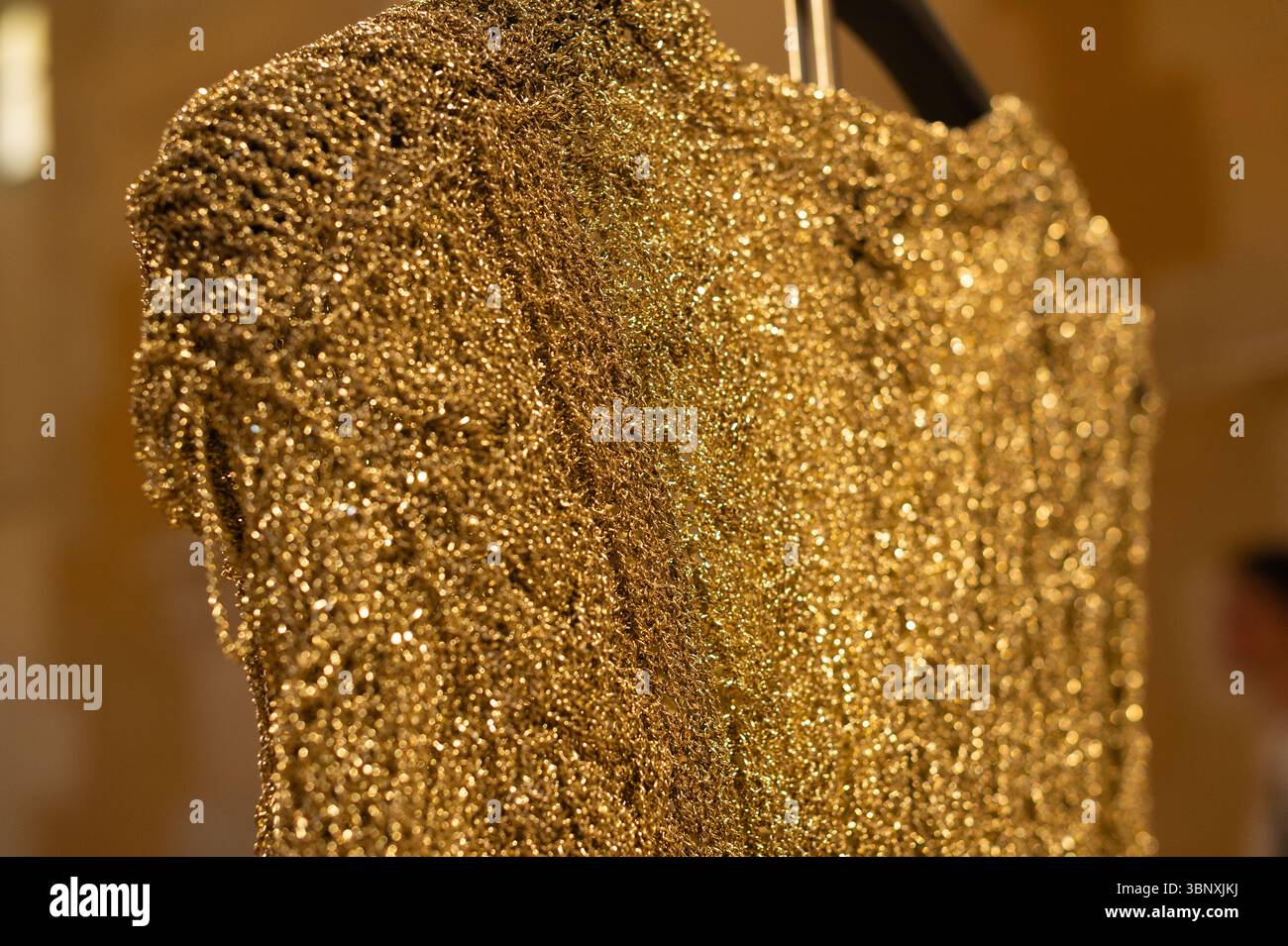 Gros plan d'une robe texturée en or exposée à l'exposition Balenciaga pendant la semaine de la Couture à Paris. Usage éditorial exclusif. Banque D'Images