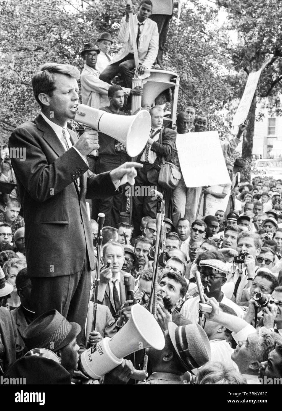 Le Procureur général Robert F. Kennedy s'adresse à une foule diversifiée à travers un mégaphone devant le ministère de la Justice à Washington, D.C. lors d'une manifestation pour les droits civiques organisée par le Congrès de l'égalité raciale. 14 juin 1963. Banque D'Images
