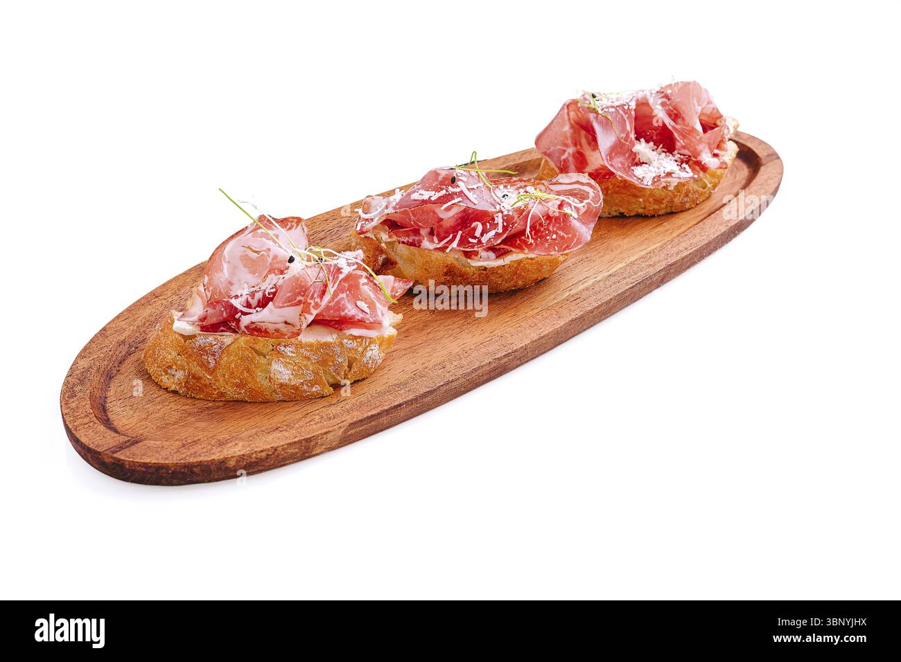 La nature morte de la nourriture, le jambon séché est magnifiquement disposé sur des morceaux de pain croustillants, garni d'herbes fraîches. Ce plat de tapas appétissant met en valeur les cuis espagnols Banque D'Images