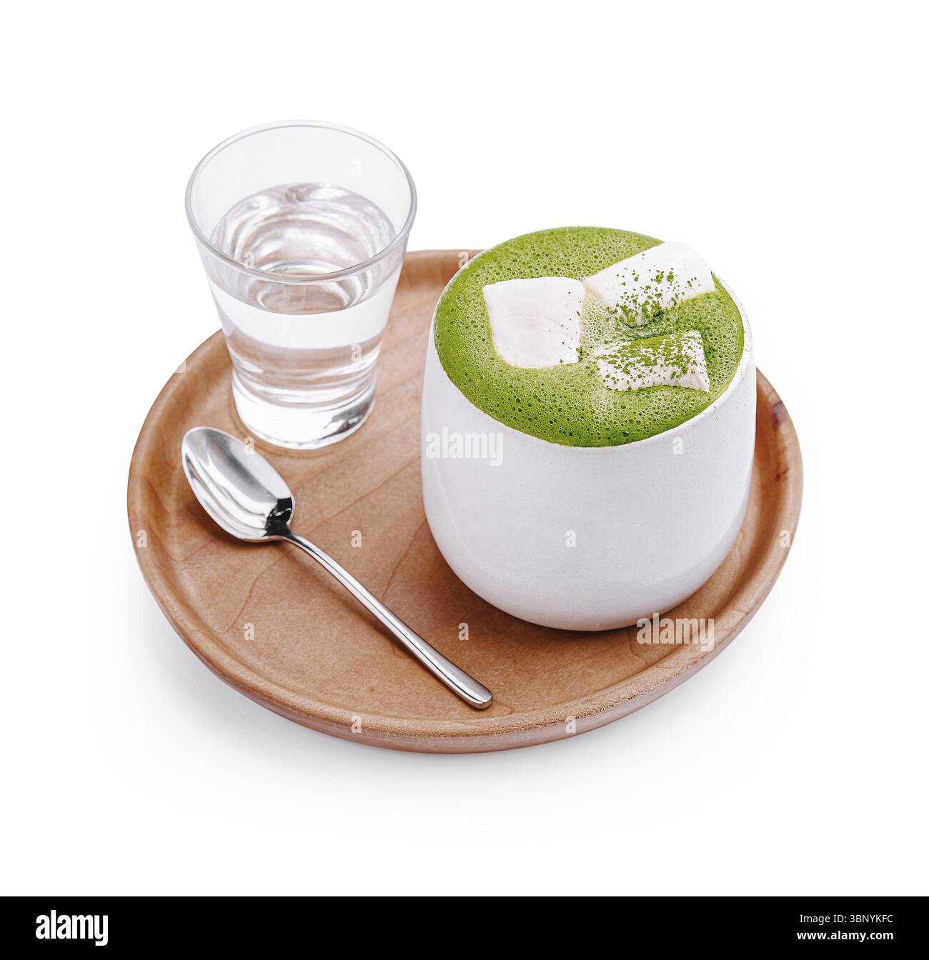 Food Still-Life, Un dessert matcha vibrant surmonté de cubes de crème douce est présenté sur une assiette en bois, avec un verre d'eau placé à côté. Ce de Banque D'Images