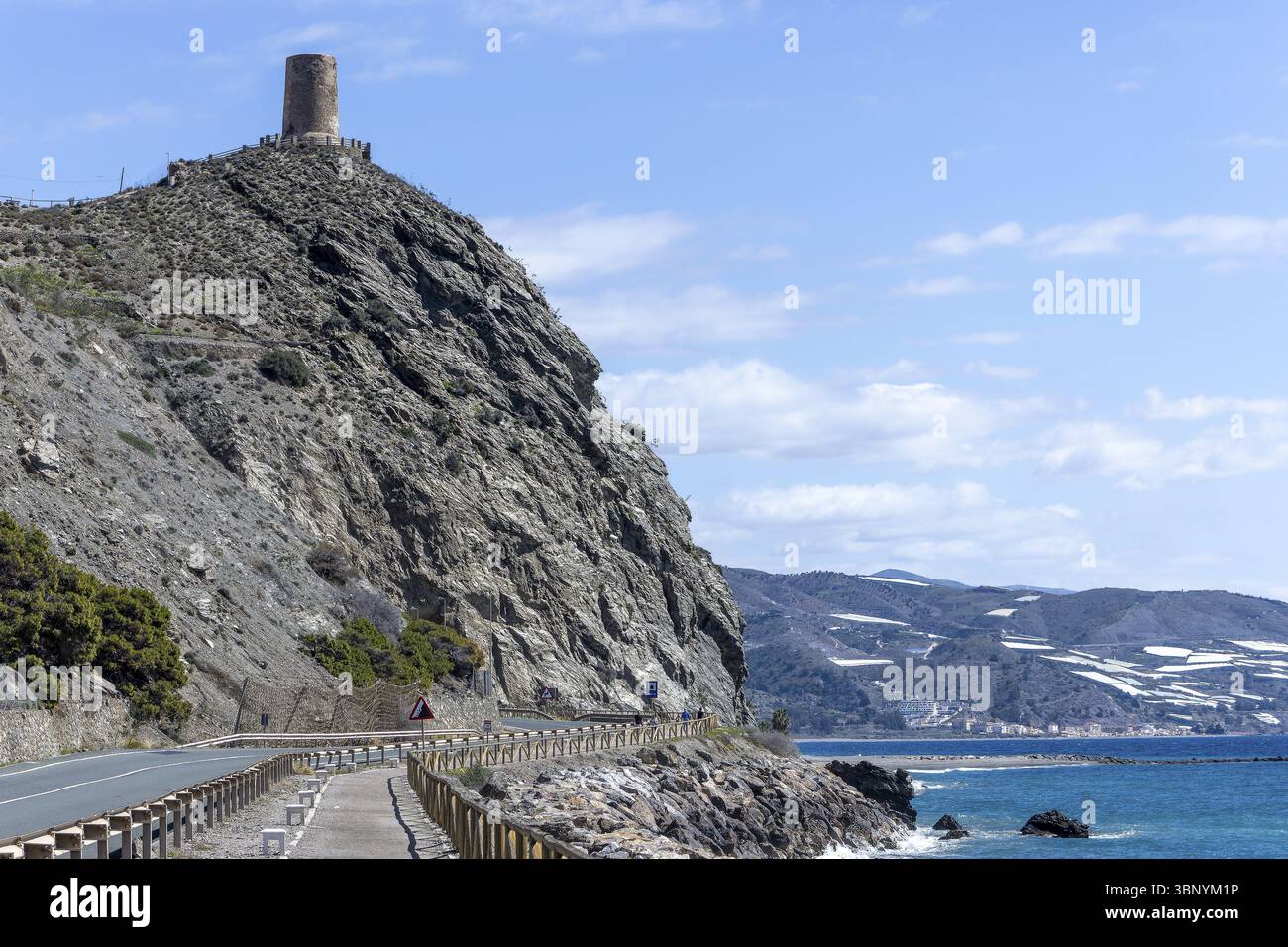 Promenade avec main courante en bois et colline avec tour en pierre Torre Cautor avec la mer bleue et le ciel en arrière-plan, Castillo de Banos de Abajo, Polopos, G. Banque D'Images