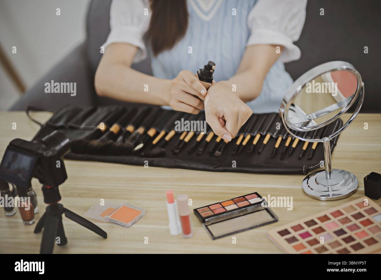 Blogueur beauté. Joyeux vlogger asiatique montre des produits cosmétiques donnant des conseils pour son blog beauté Banque D'Images