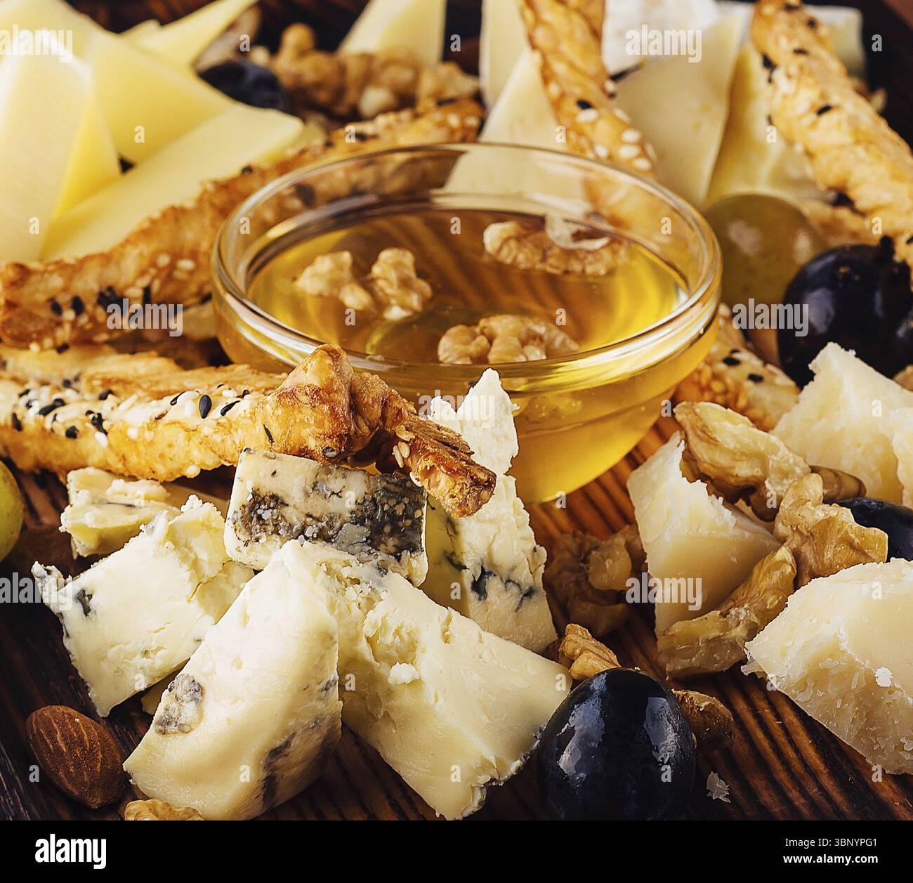 Nature morte, assiette de fromage avec miel, raisins et noix Banque D'Images