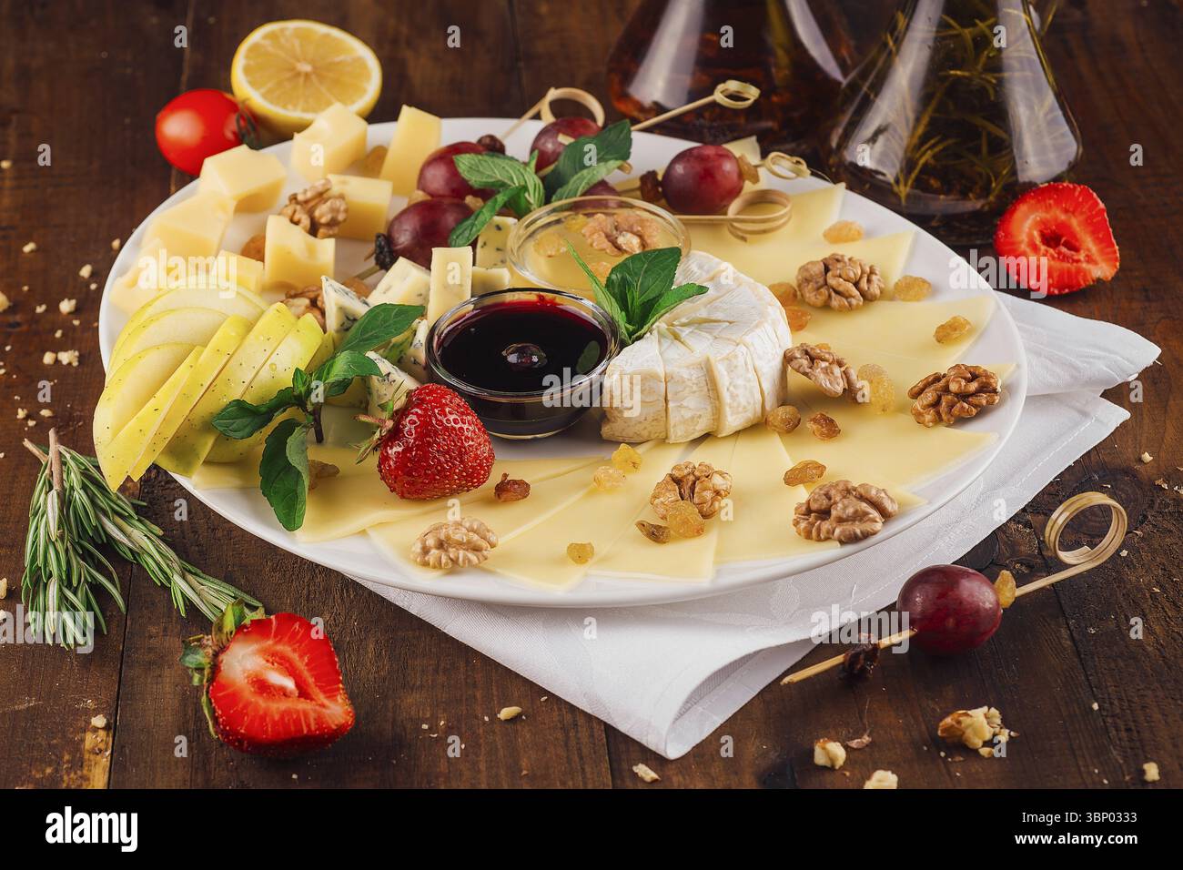 Nourriture Still-Life, assiette de fromage présentant une variété de fromages avec des fruits et des noix sur une table en bois Banque D'Images