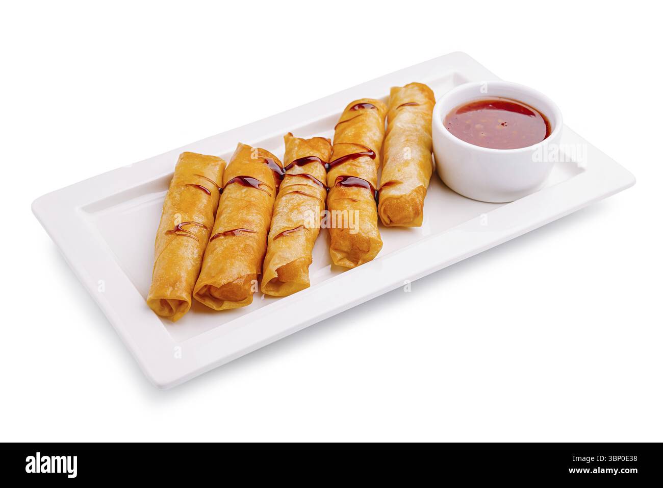 Nature morte, Un plateau de rouleaux de printemps croustillants est composé de rouleaux bruns dorés parfaitement disposés à côté d'un petit bol de sauce sucrée. Idéal fo Banque D'Images