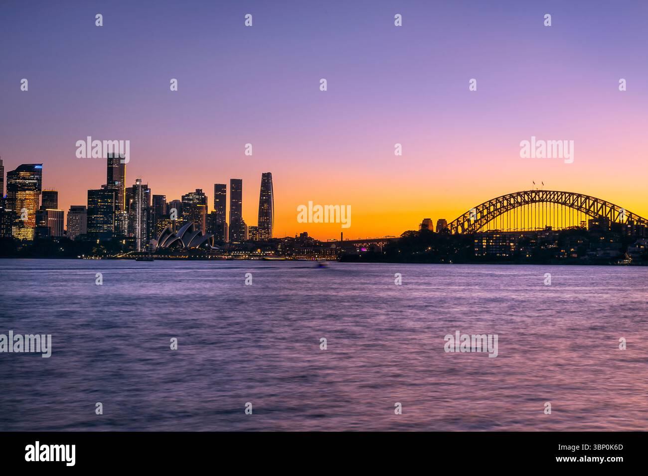 Coucher de soleil rose et chaud sur les gratte-ciel du quartier des affaires de Sydney à travers le port en Australie. Banque D'Images
