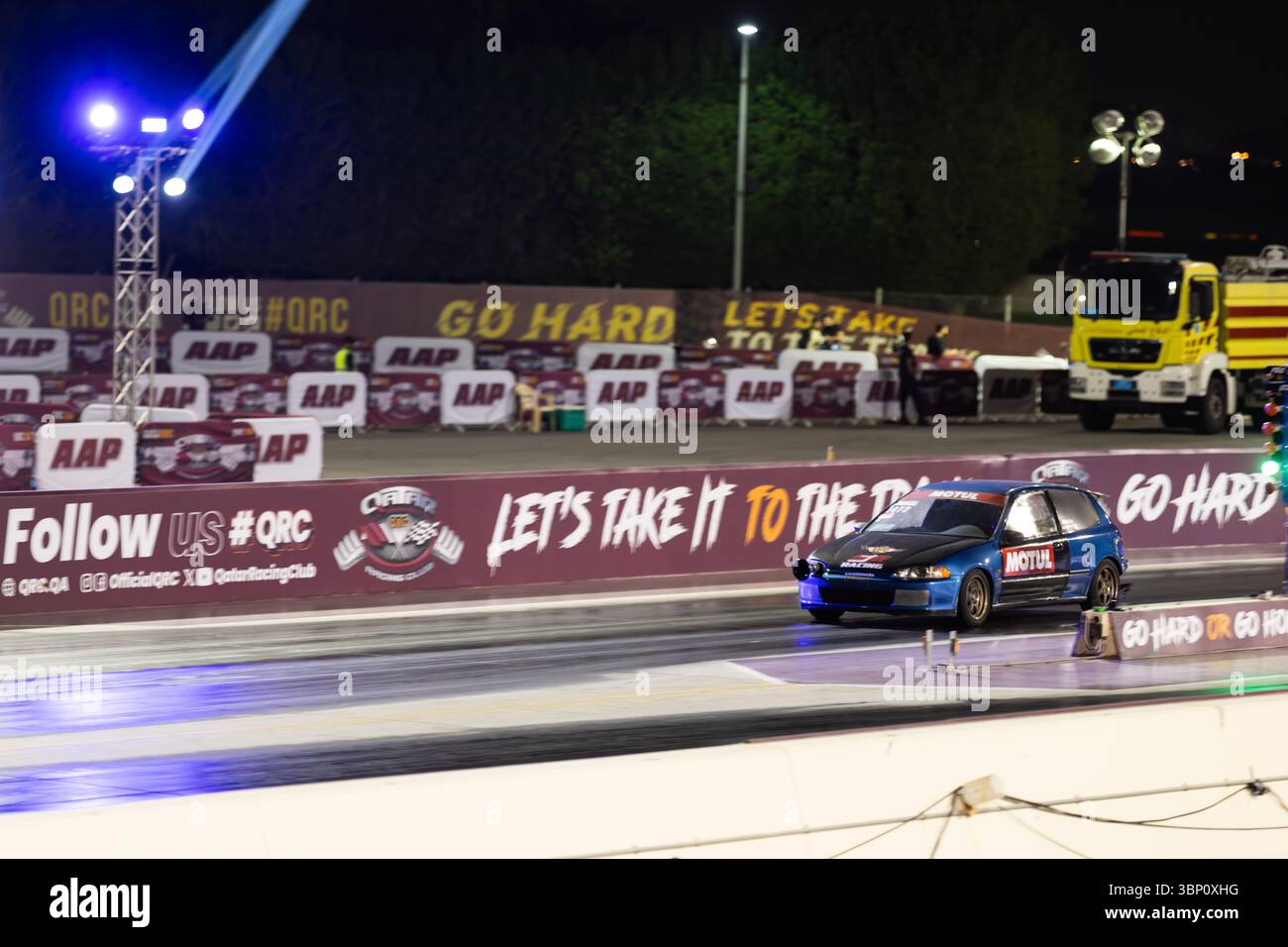 Motion blur course de dragsters nocturne mettant en vedette des voitures en compétition sur la piste avec des spectateurs à proximité Banque D'Images