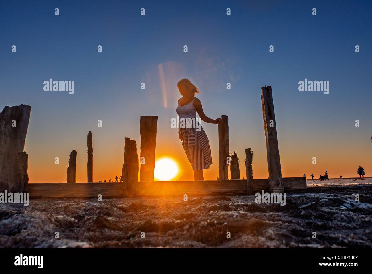 Tranquille solitude Une fille dans une robe marche le long des rives d'un lac salé au coucher du soleil. Banque D'Images