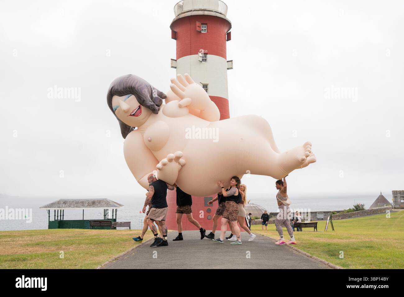 USAGE ÉDITORIAL UNIQUEMENT vue générale des membres du gymnase Powerbuilding transportant un béryl Cook gonflable au 'Hello Sailor' de Jeremy Deller, une célébration de l'art et de la communauté au Tinner Lido de Plymouth, présentée par The Box Plymouth et la National Gallery dans le cadre de leur projet bicentenaire 'Triumph of Art'. Date de la photo : samedi 5 juillet 2025. Banque D'Images