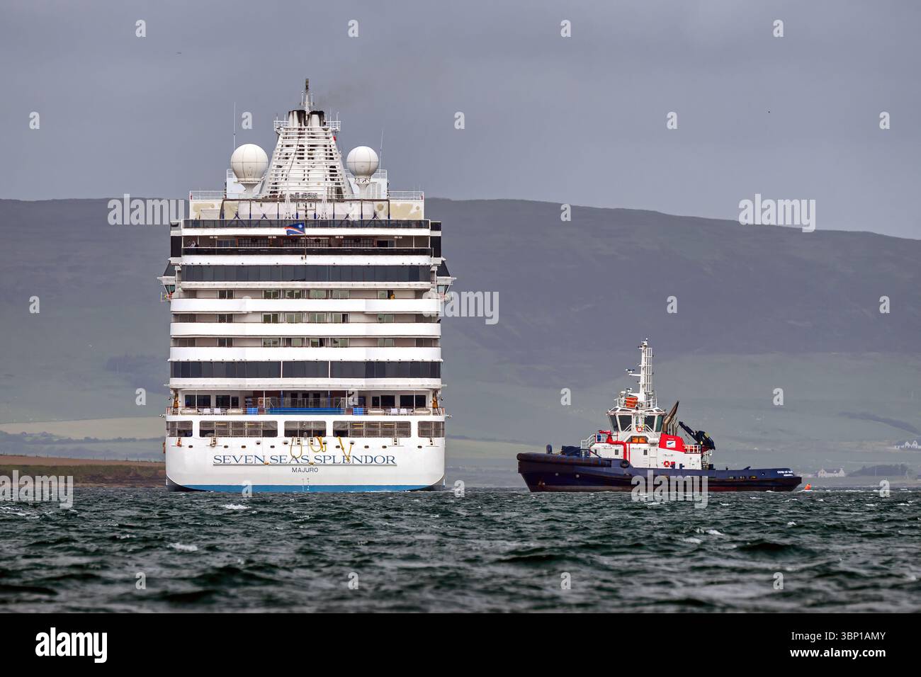 Le navire de croisière Seven Seas Splendor (Regent Cruises) accoste à Kirkwall, Orcades avec le remorqueur Odin de Scapa debout. Banque D'Images