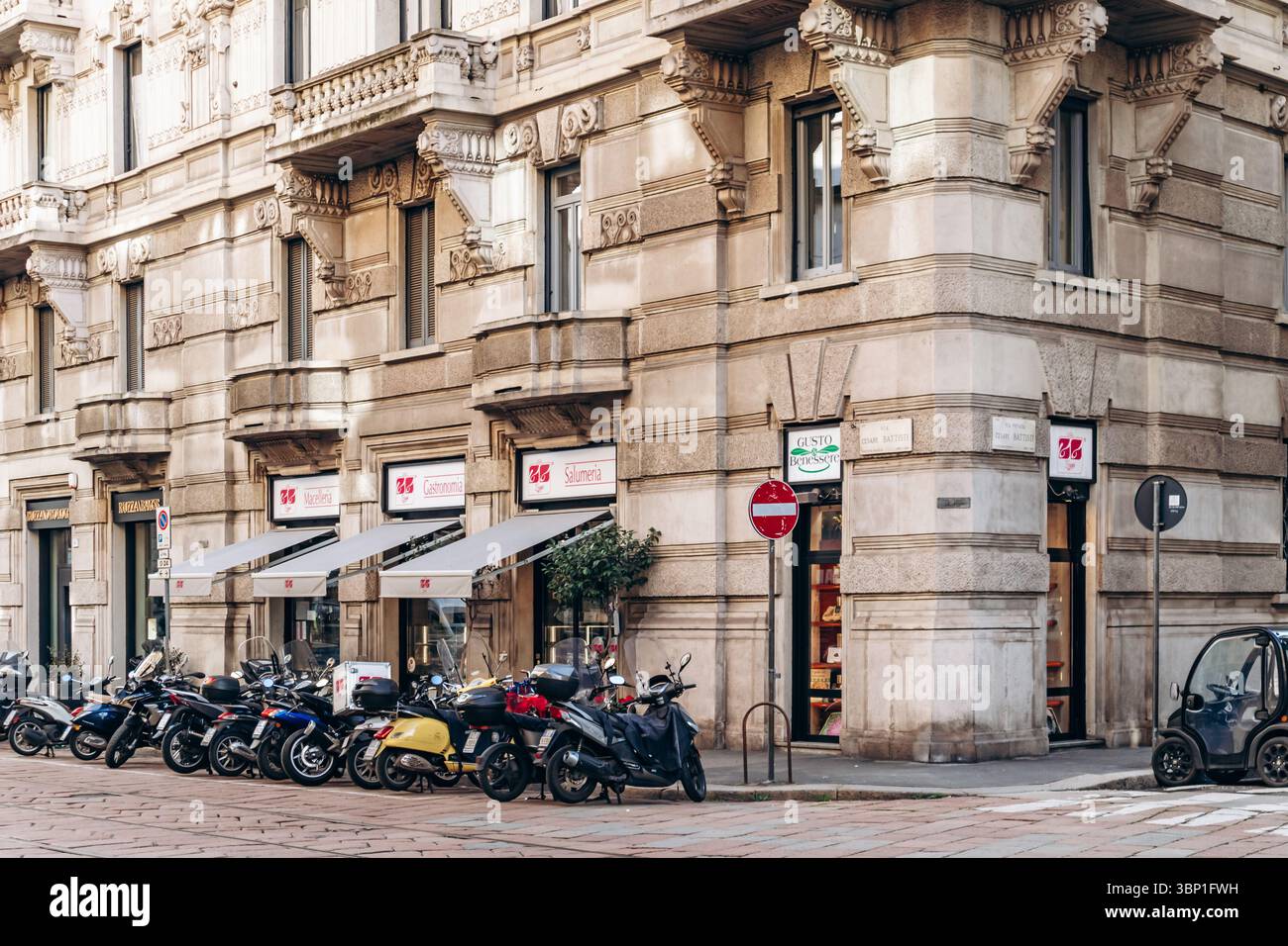 Milan, Italie - 19 mars 2025 : rue centrale de Milan avec bâtiments historiques, boutiques et scooters Banque D'Images