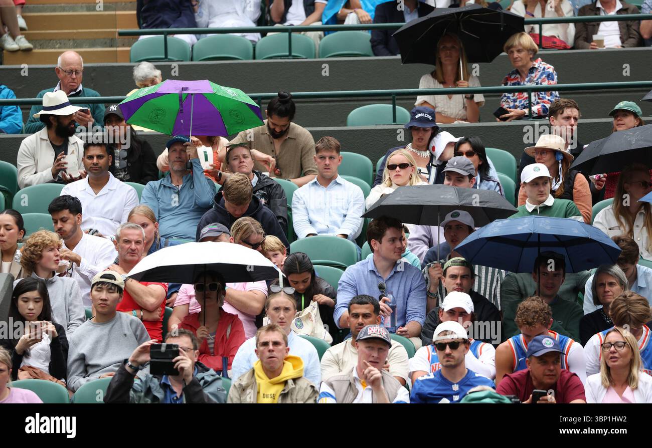 Londres, Royaume-Uni. 05 juillet 2025. Les fans de tennis s'abritent sous des parapluies après que la pluie a arrêté le match le sixième jour des Championnats de Wimbledon 2025 à Londres le samedi 5 juillet 2025. Photo de Hugo Philpott/UPI crédit : UPI/Alamy Live News Banque D'Images