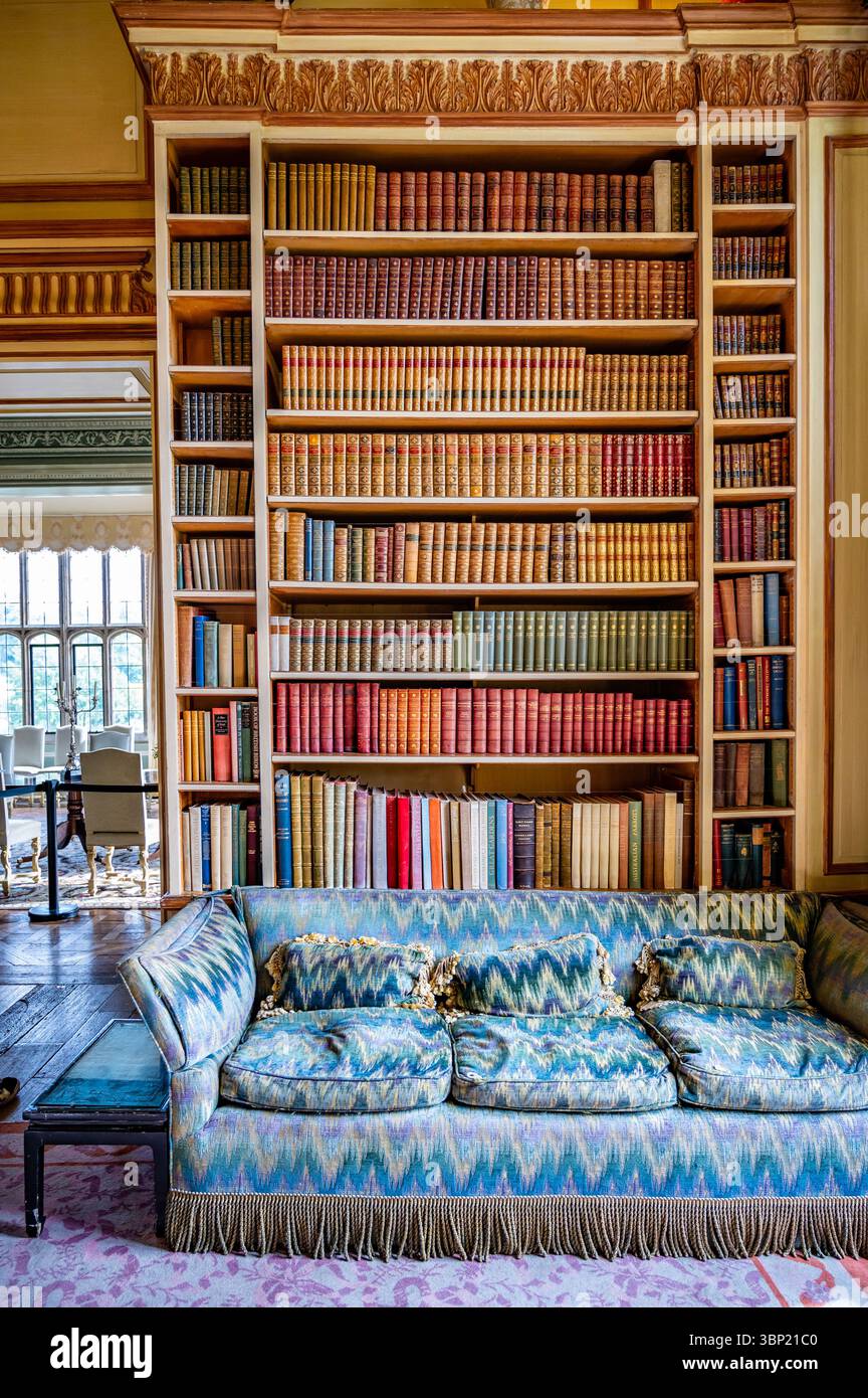 L'intérieur opulent de la bibliothèque du château de Leeds, Kent, avec des étagères pleine de livres anciens et un canapé coloré Banque D'Images