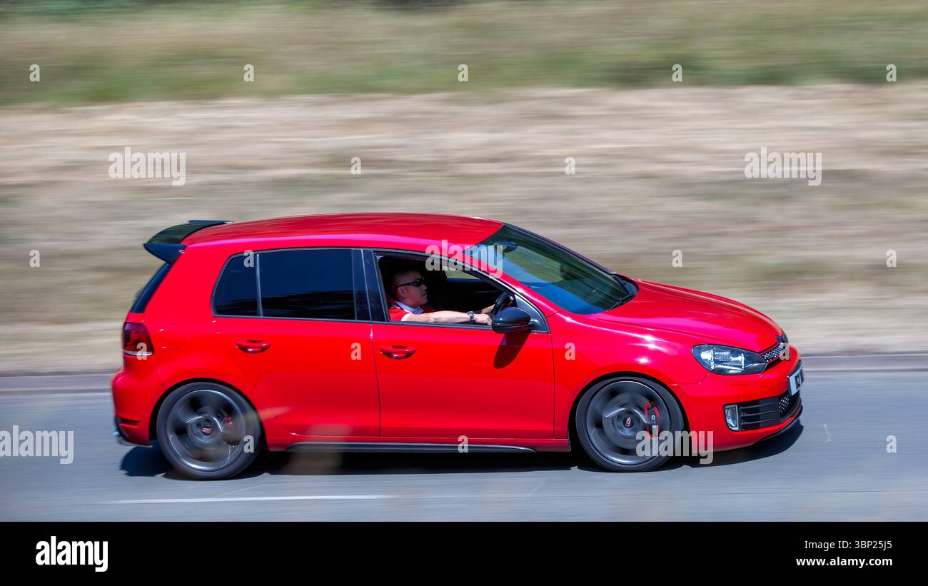Milton Keynes,Bucks,UK - 4 juillet 2025 : 2012 voiture rouge Volkswagen Golf gti conduisant sur une route britannique Banque D'Images