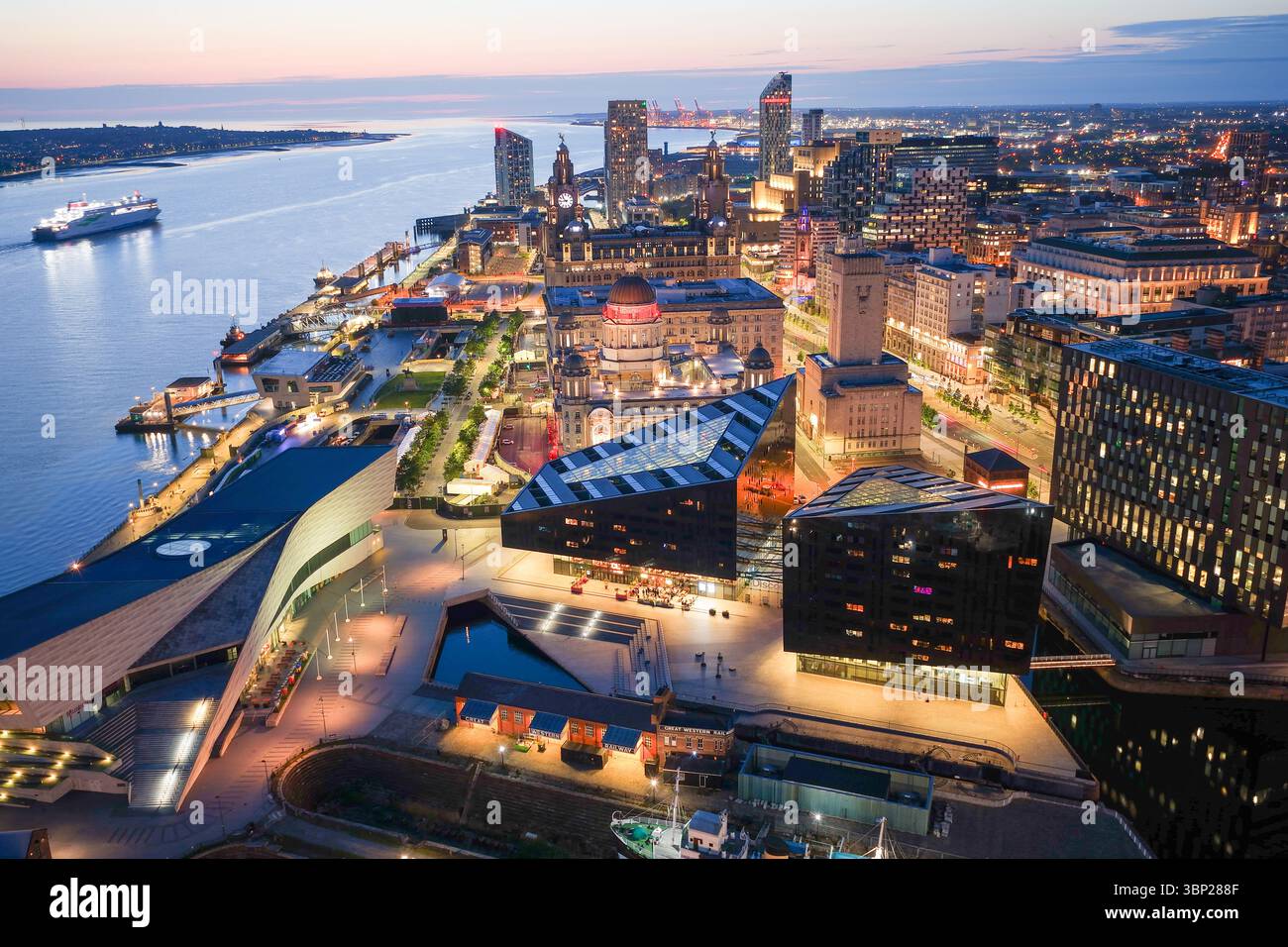 Image aérienne de la ligne d'horizon illuminée de Liverpool avec un navire voyageant sur la rivière Mersey Banque D'Images