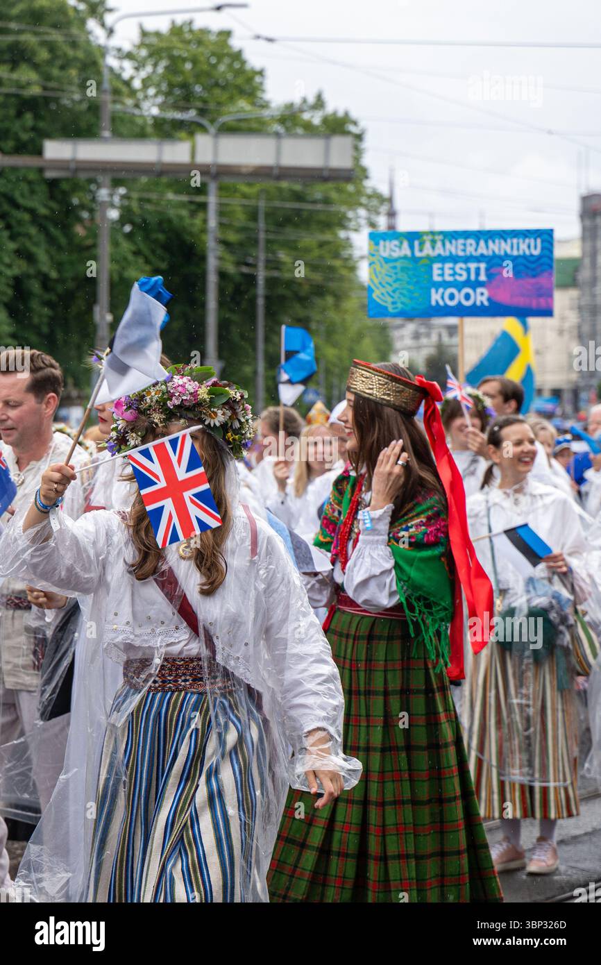 Participants aux costumes folkloriques agitant des drapeaux britanniques et estoniens, avec la bannière « USA Lääneranniku Eesti Koor », procession du Festival de la chanson à Tallinn Banque D'Images